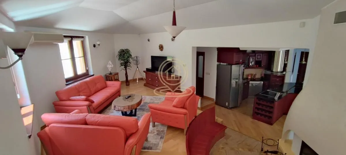 Living room with red leather sofas and an open kitchen in the background.