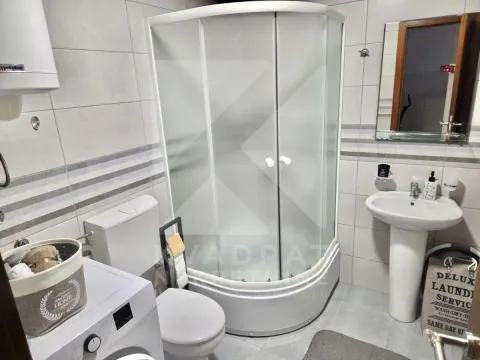 Bathroom equipped with a shower cabin, sink, toilet, and washing machine. - image 5