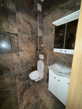 Moderno opremljeno kupatilo sa tuš kabinom i keramičkim pločicama u tonovima mermera. - image 7
