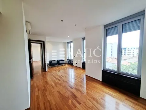 Spacious empty room with parquet flooring and large windows. - image 2