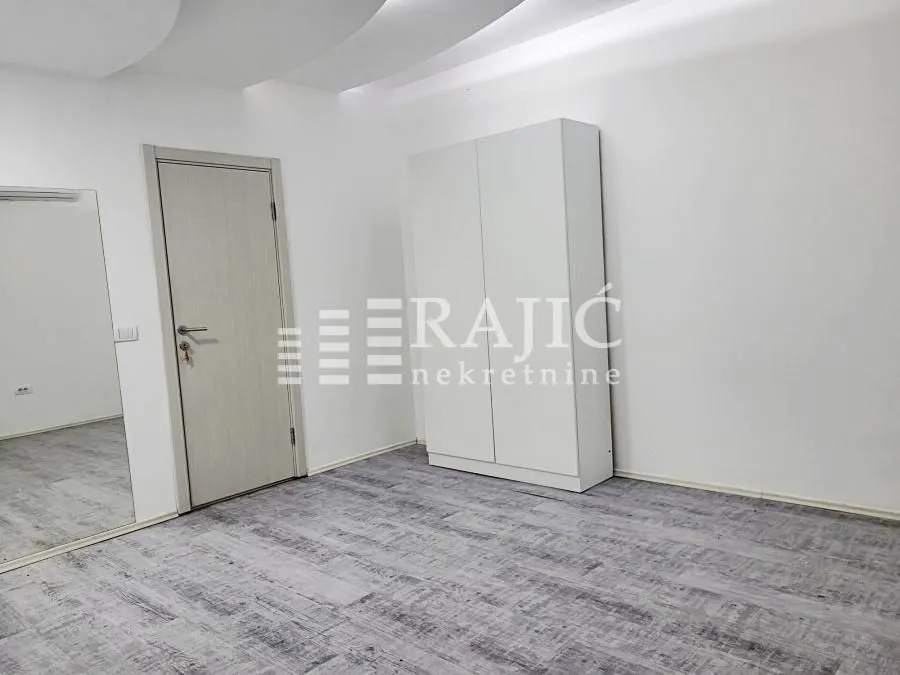 Bright bedroom with a white wardrobe, a door, and a large mirror.