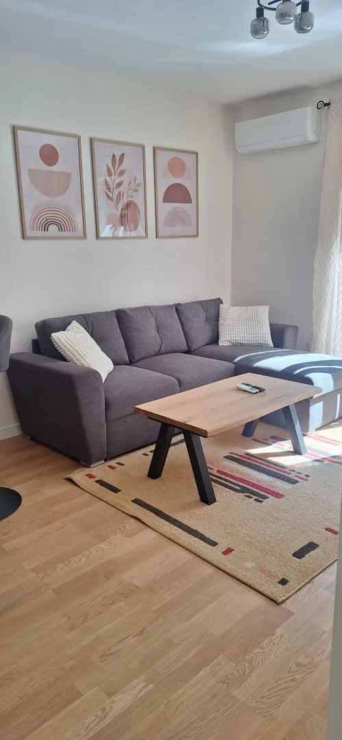 Living room with a corner sofa, wooden coffee table, and decorative wall art.
