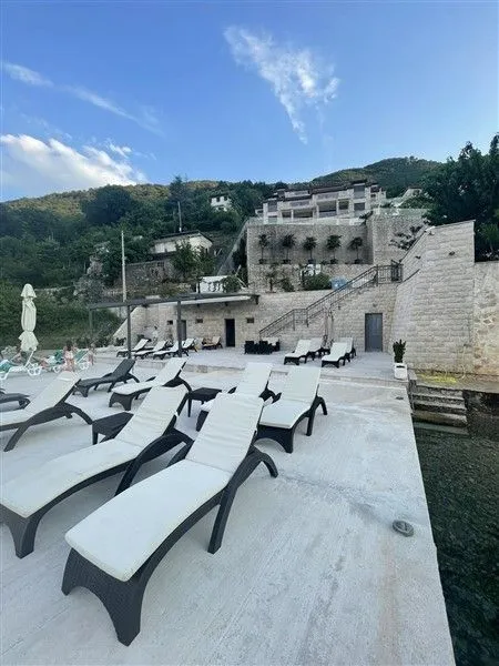 Terasa sa ležaljkama ispred kamene zgrade na obali.