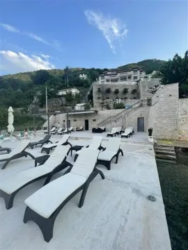 Terasa sa ležaljkama ispred kamene zgrade na obali. - image 15