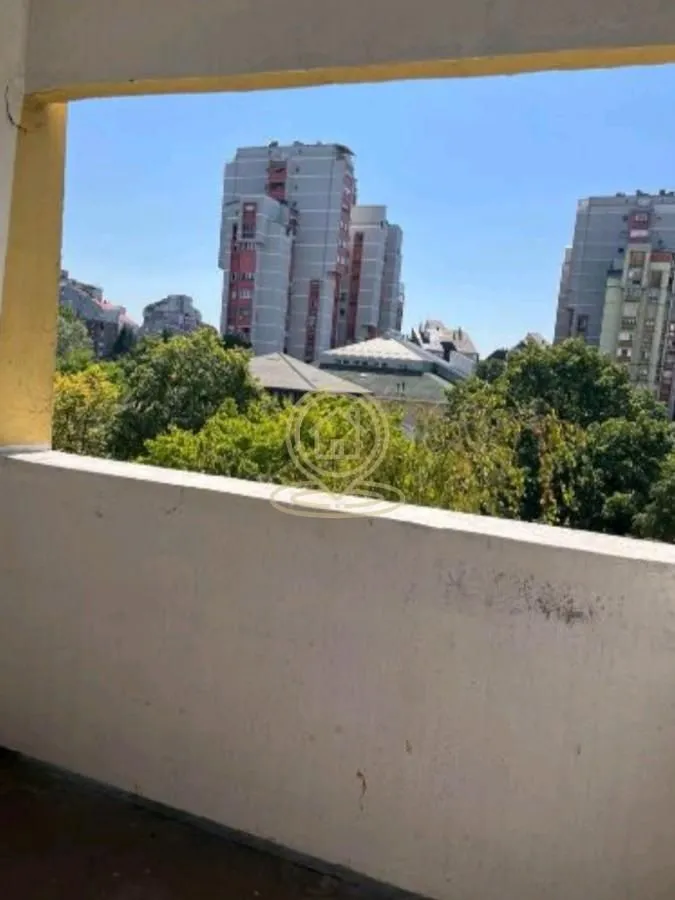Pogled sa balkona na okolne zgrade i zelenilo.