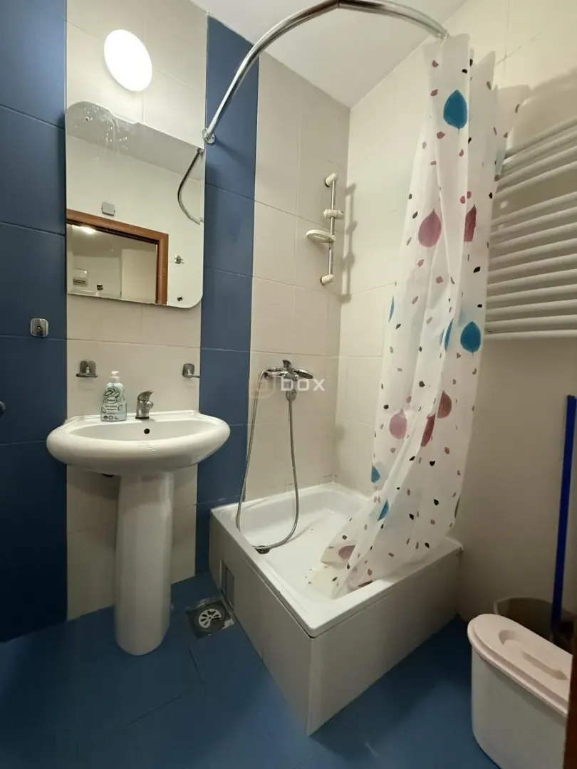 Bathroom equipped with a washbasin, mirror, and a shower with a curtain.