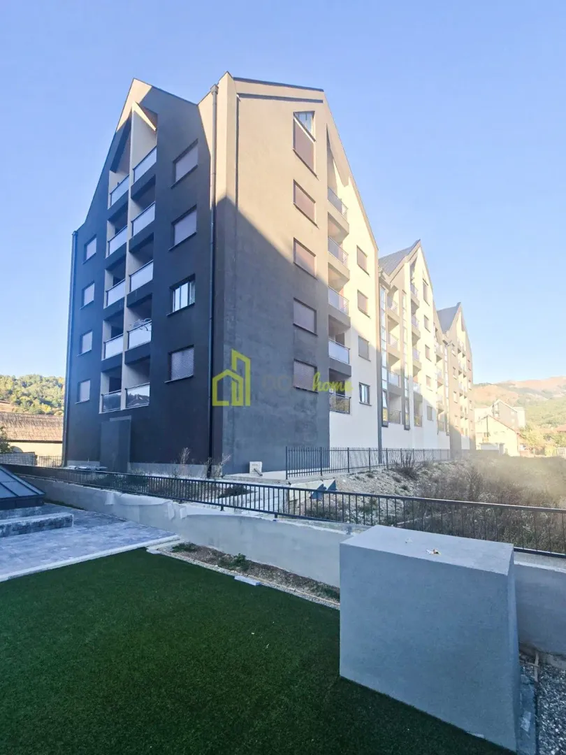 Pogled na spoljašnjost moderne stambene zgrade sa terasama i uređenim dvorištem.