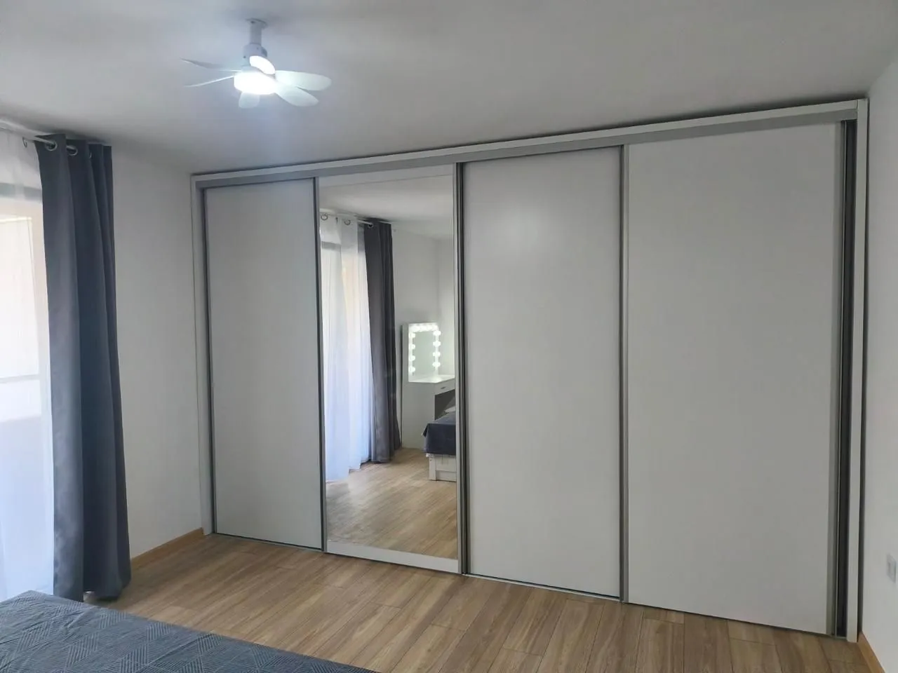 Bedroom with a large fitted wardrobe and wooden flooring.