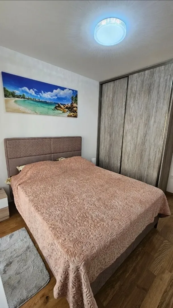 Namještena spavaća soba sa bračnim krevetom, ormarom i slikom na zidu.