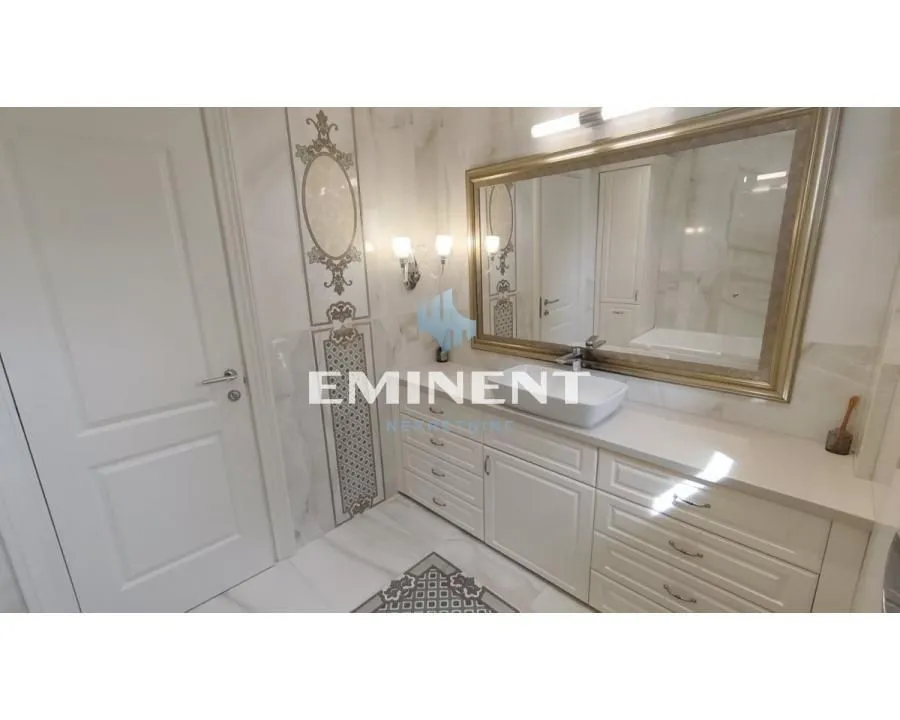 Modern bathroom with white furniture, washbasin, and a large mirror.