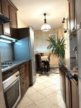 Long kitchen with wooden cabinets and built-in appliances. - image 5