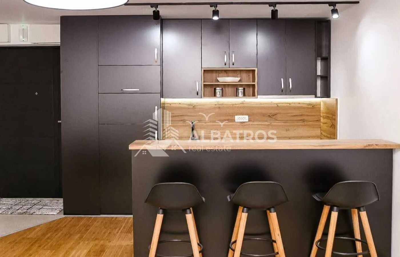 Modern kitchen with a bar counter and black units.