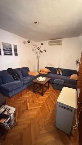 Dnevna soba sa garniturom za sedenje, parketom i klima uređajem.