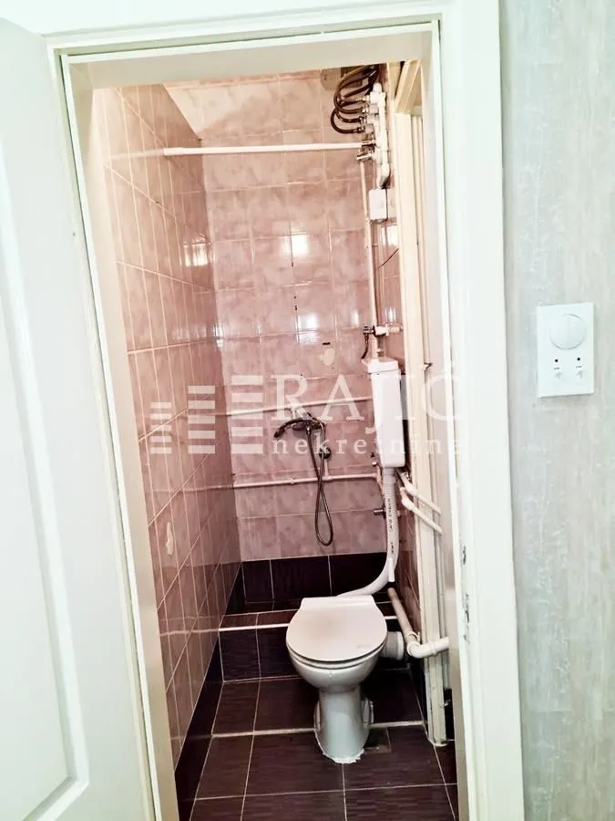 Manje kupatilo sa pločicama, wc šoljom i sanitarnim instalacijama.