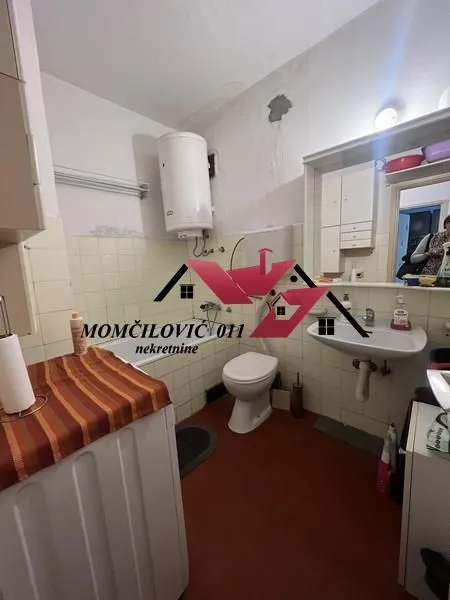 Starije opremljeno kupatilo sa kadom, umivaonikom, WC šoljom i bojlerom.
