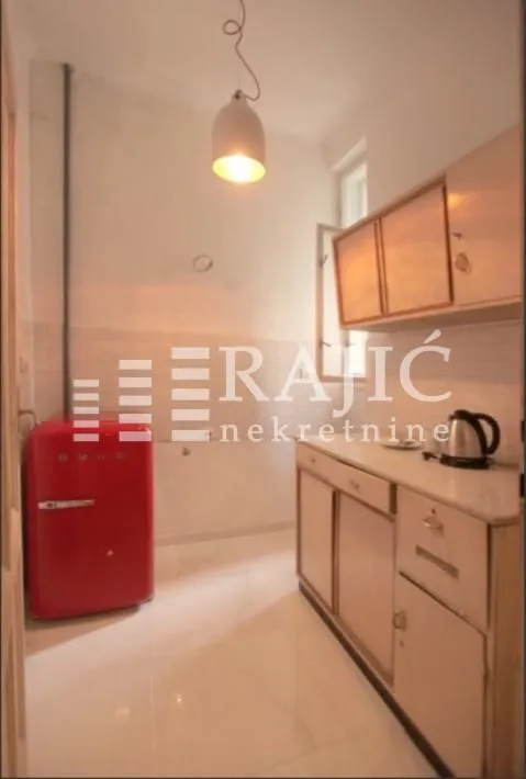 Small kitchen with white cabinets and a red refrigerator.