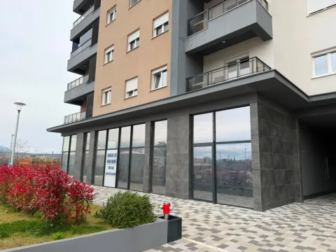 Exterior view of a modern residential and commercial building with large glass shopfronts on the ground floor. - image 2