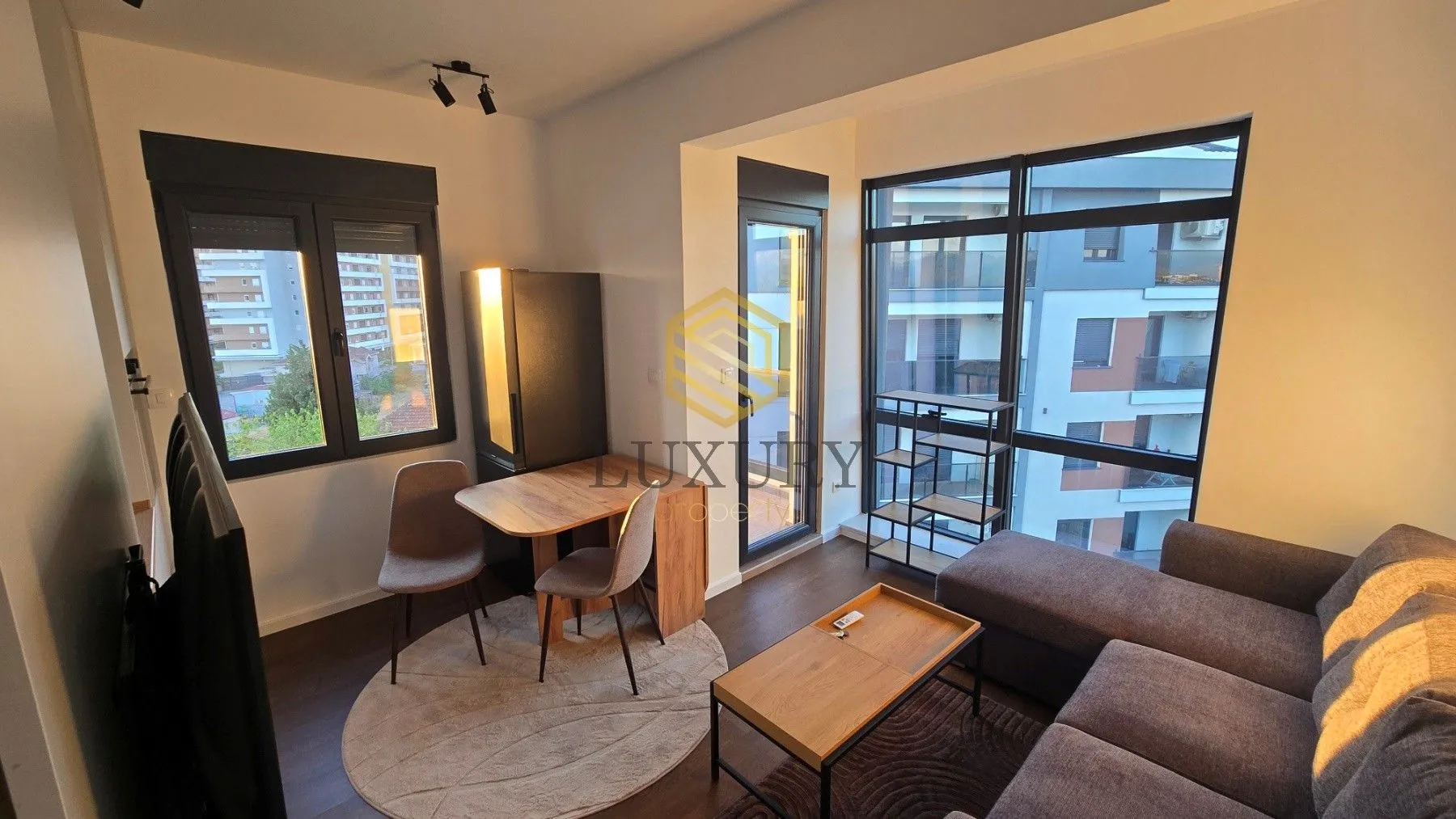 Modern living room with a sofa, dining table, and large windows.