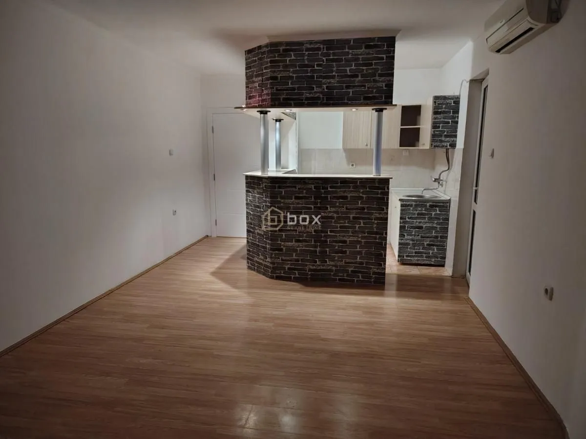 Small kitchen with a brick bar and wooden flooring.