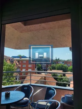 Namešten balkon sa stolom i stolicama i pogledom na okolne zgrade. - image 4