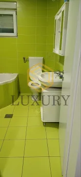Small bathroom with green tiles, washbasin and toilet. - image 9