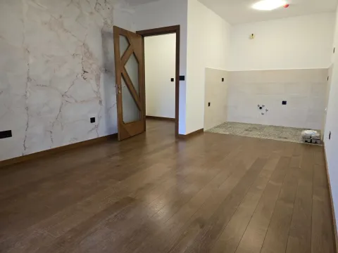 Empty room with wooden flooring and ceramic tiles in the corner. - image 2