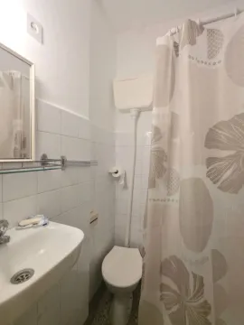 Small bathroom with a sink, toilet, and shower curtain. - image 4