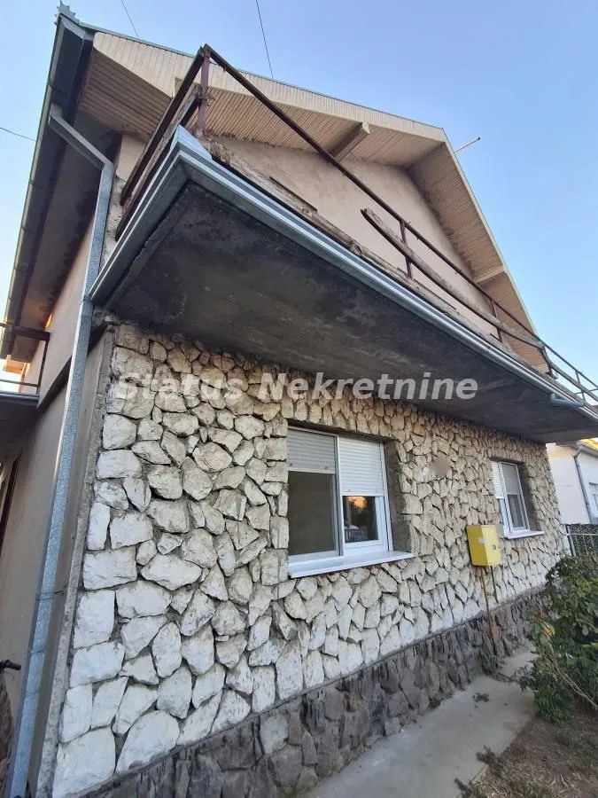 Spoljašnji izgled kuće sa kamenom fasadom i balkonom.
