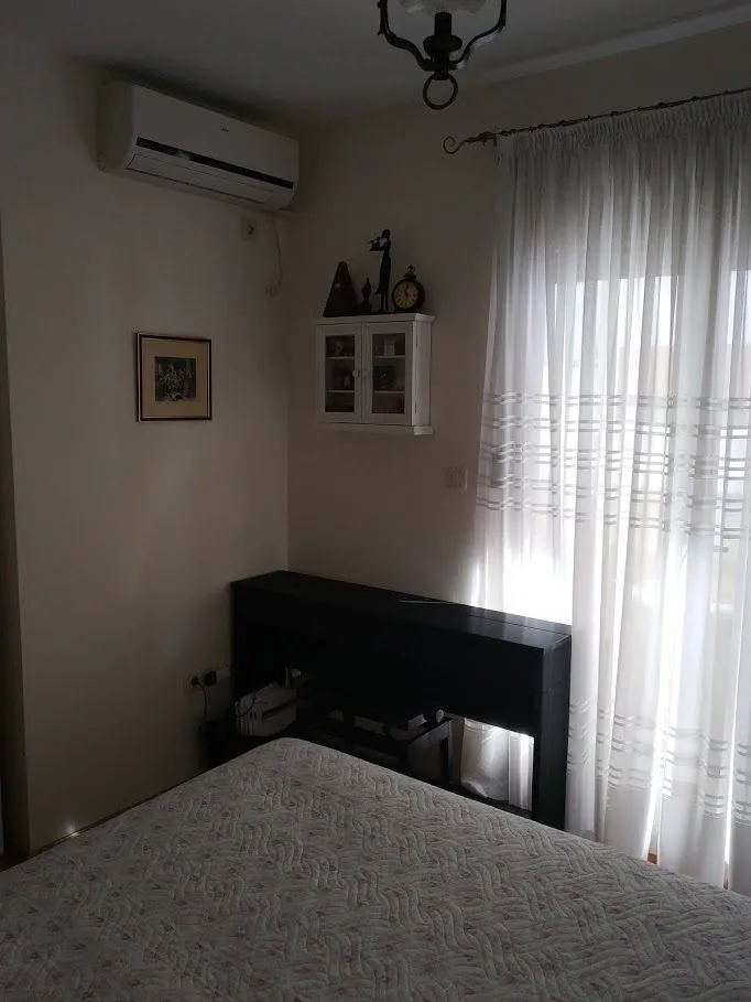 Dio spavaće sobe sa krevetom, prozorom i klima uređajem.