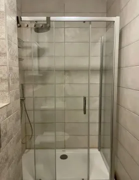 Moderna tuš kabina sa staklenim paravanom i keramičkim pločicama na zidu. - image 15