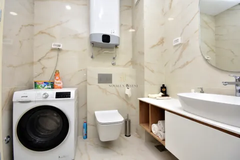 Modernly equipped bathroom with a shower, washbasin, and washing machine. - image 10