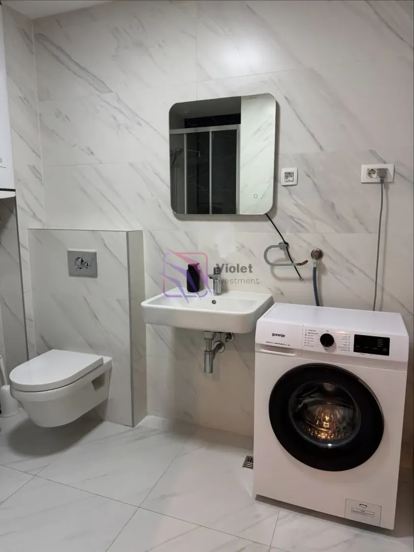 Savremeno opremljeno kupatilo sa umivaonikom, WC šoljom i veš mašinom.