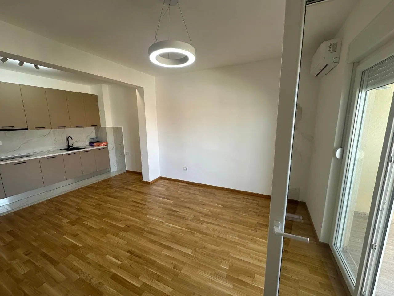 Living room with kitchen and wooden flooring.