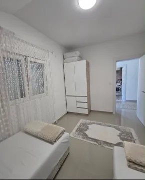 Bright bedroom with beds, wardrobe, and a view of the hallway. - image 5