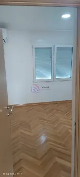 An empty room with wooden parquet flooring and a window viewed from the doorway. - image 4