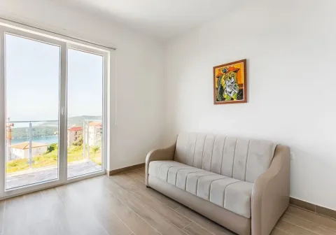 Svijetla prostorija sa modernim kaučem i izlazom na balkon sa pogledom. - image 2