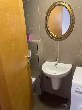 Small bathroom with a sink, mirror, and tiled walls. - image 11