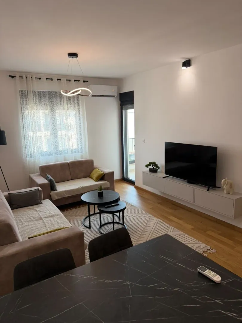 Furnished living room with sofa set, TV, and dining table.