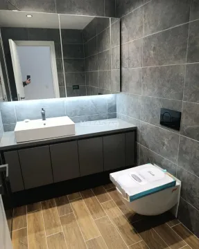 Savremeno opremljeno kupatilo sa tamnim pločicama, umivaonikom i ugrađenom sanitarijom. - image 7