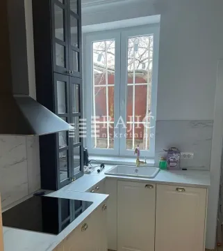 Compact kitchen with a sink, built-in cooktop, and upper cabinets next to the window. - image 2