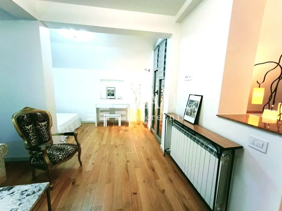 Living room with wooden flooring, a stylish armchair, and a desk.