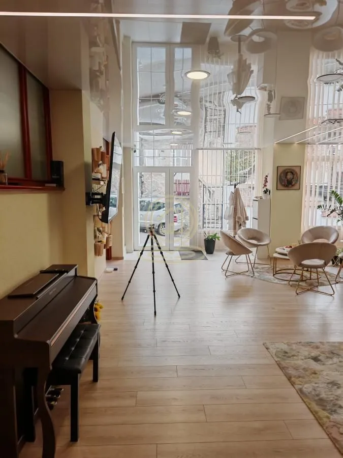 Spacious living room with seating area, piano, and high ceiling.