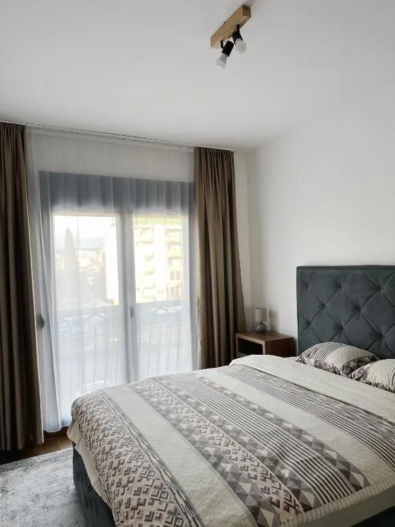 Spavaća soba sa bračnim krevetom i balkonskim vratima.