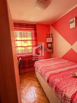 Manja spavaća soba sa krevetom, ormarom i prozorom sa crvenim zavjesama. - image 9