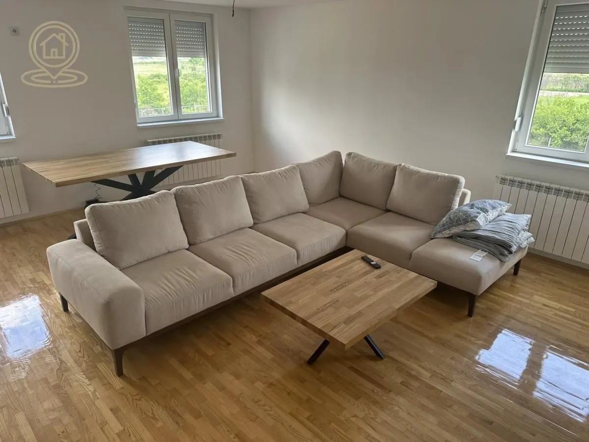 Living room with a sectional sofa, wooden coffee table, and dining table.