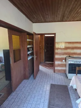 Starija kuhinja sa pločicama na zidu, drvenim plafonom i vratima koja vode u druge prostorije. - image 11