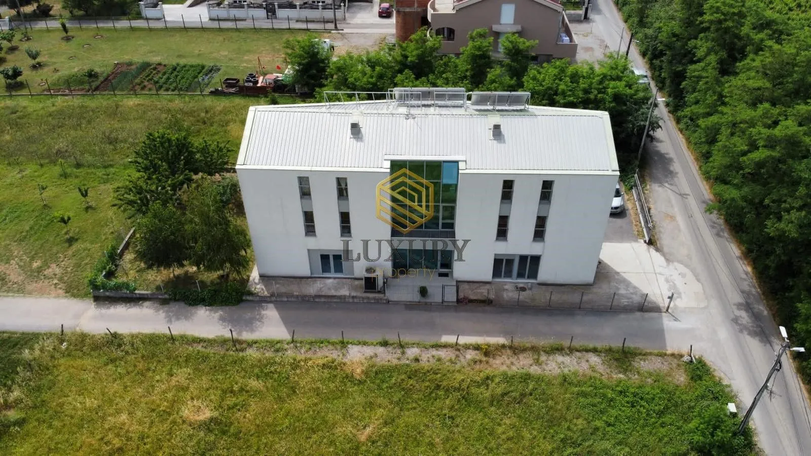 Aerial view of the exterior of a modern residential building with a yard.