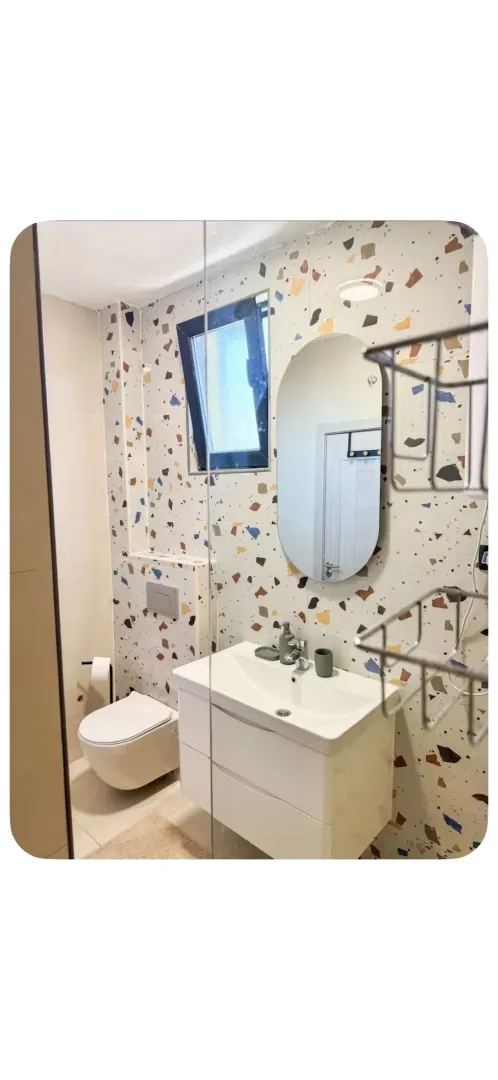 Moderne kupatilo sa umivaonikom, WC šoljom i pločicama sa šarom teraca.