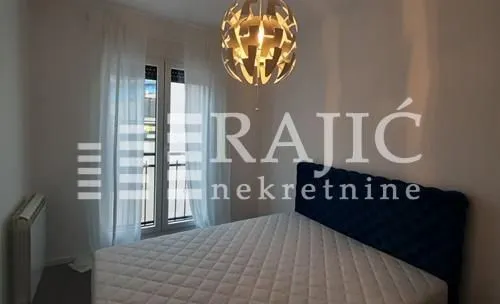 Bedroom with a double bed, window, and modern chandelier.