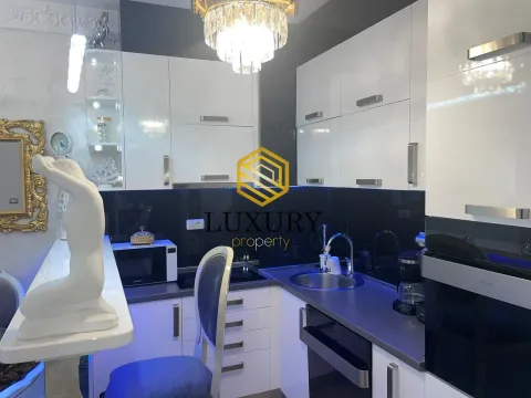 Modern kitchen with white cabinetry, dark countertops, and built-in lighting. - image 4